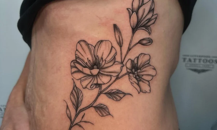 Delicate blackwork floral rib tattoo