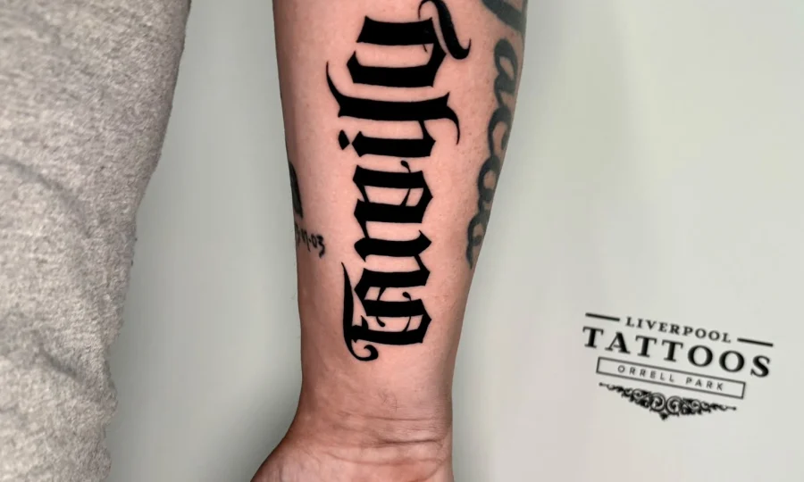 Old English gothic lettering forearm tattoo by Liverpool artist Demi