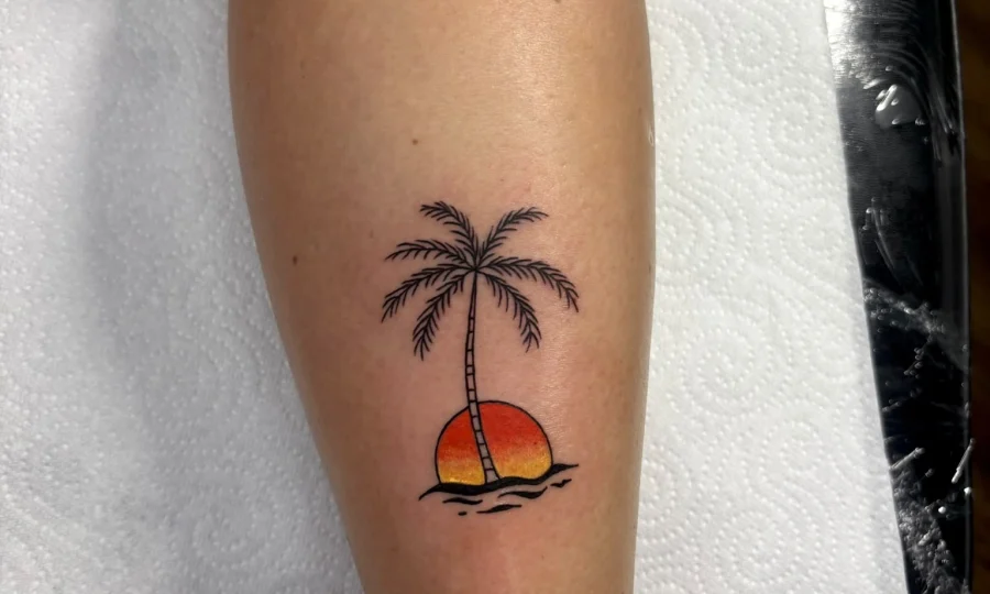Minimalist color palm tree and sunset calf tattoo by artist Demi