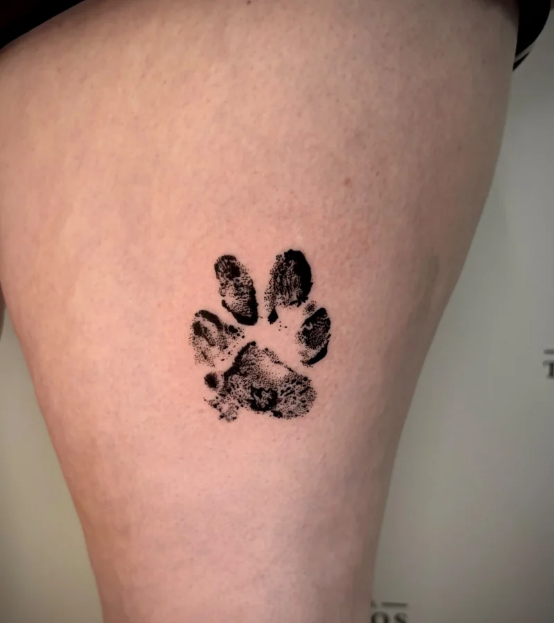 Small black paw print memorial tattoo by Liverpool artist Demi